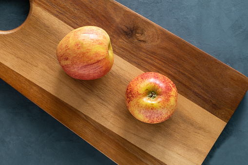 Two red beautiful apples on the cutting board.