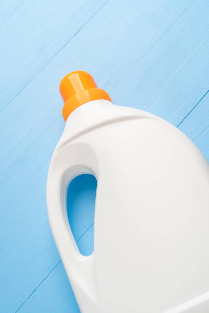istock White plastic bottle with a bright orange cap with detergent for washing on a wooden light blue background close-up 1224656063