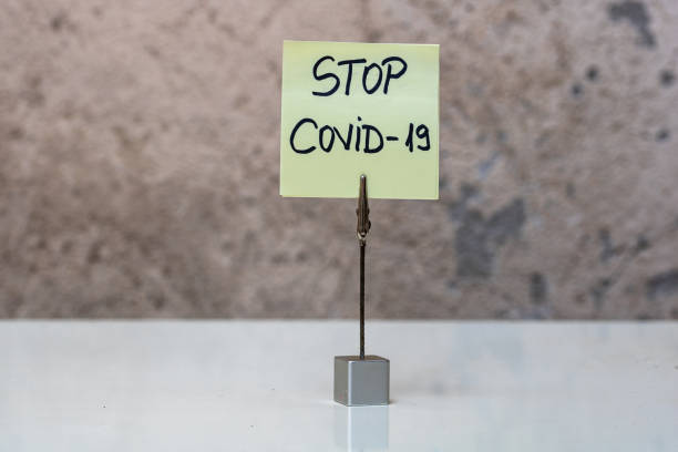 istock Stop covid-19 handwriting text on memo post reminder isolated with copy space. 1224659751