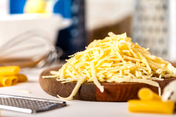 Pile of grated cheese on a cutting board close-up Pile of grated cheese on a cutting board close-up. Cooking pasta with grated cheese. Cheese and kitchen utensils on the table. shredded mozzarella stock pictures, royalty-free photos & images