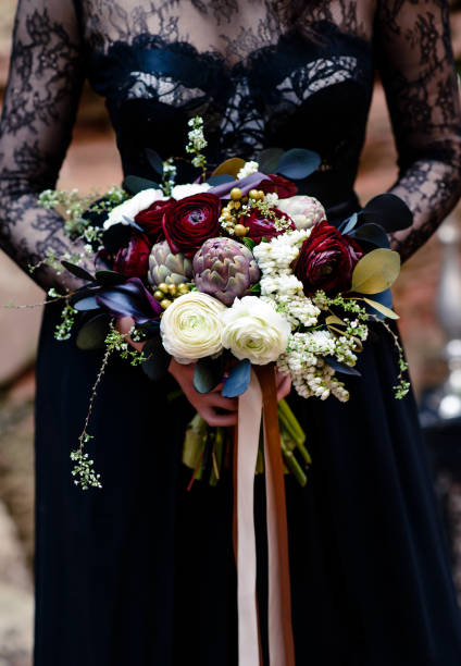 bouquet nelle mani di una ragazza con un vestito nero. nero magico, bellezza gotica. halloween, bouquet di vedove nere - goth foto e immagini stock