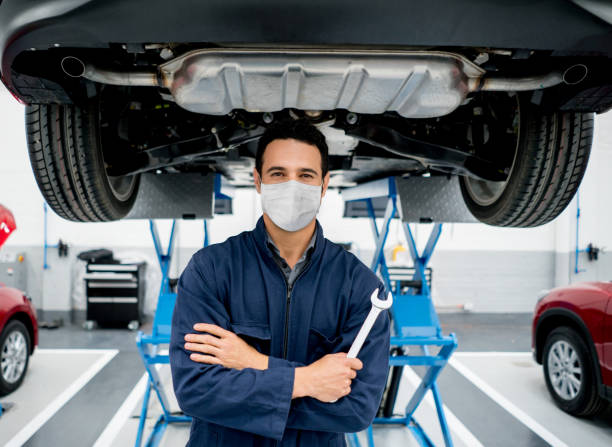 Mechanic working at a car garage wearing a facemask to avoid the spread of coronavirus Portrait of a Latin American mechanic working at a car garage wearing a facemask to avoid the spread of coronavirus â pandemic lifestyle concepts chassis photos stock pictures, royalty-free photos & images