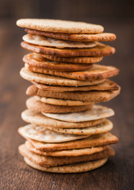istock Stack of various organic crispy wheat, rye and corn flatbread crackers with sesame and salt on wooden background. 1224669705