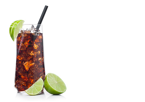 Cuba Libre Cocktail in luxury tall glass with ice cubes and slices of lime with black straw on white background.Space for text