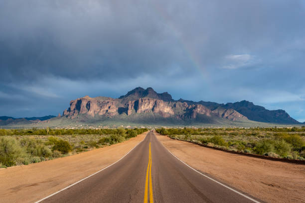 Storm Over Superstition Mountain Storm clouds gather over Superstition Mountain in Apache Junction, Arizona, producing a partial rainbow in the rays of the setting sun. sonoran desert stock pictures, royalty-free photos & images