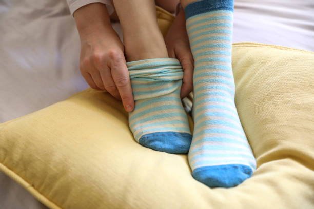 Women's beautiful socks on bed Hand wear socks of woman on bed stock photo woman putting on socks stock pictures, royalty-free photos & images