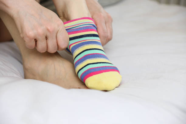 Women's beautiful socks on bed Hand wear socks of woman on bed stock photo woman putting on socks stock pictures, royalty-free photos & images