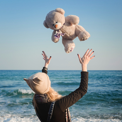 Cute nice girl with a teddy bear in her hands walking on the seashore, the concept of rest, happiness, joy, meditation, silence, loneliness.