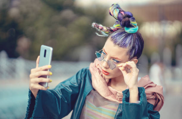 Funky girl with bizarre fashion style hair taking selfie on street Young Woman with avantgarde look bizarre fashion stock pictures, royalty-free photos & images