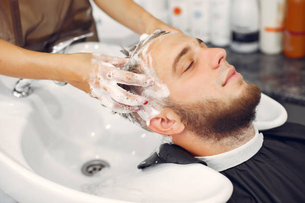 Woma washing man's head in a barbershop stock photo