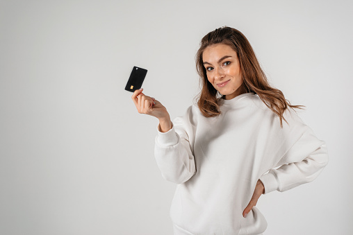 Close-up portrait of young smiling business woman holding credit card isolated on white background