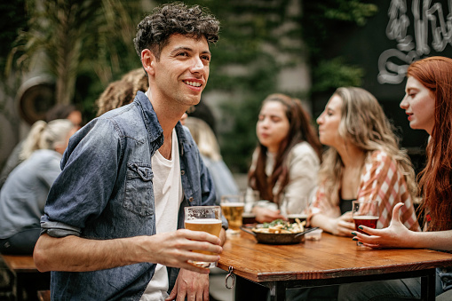 Group of happy multi-ethnic friends drinking beer at outdoor restaurant