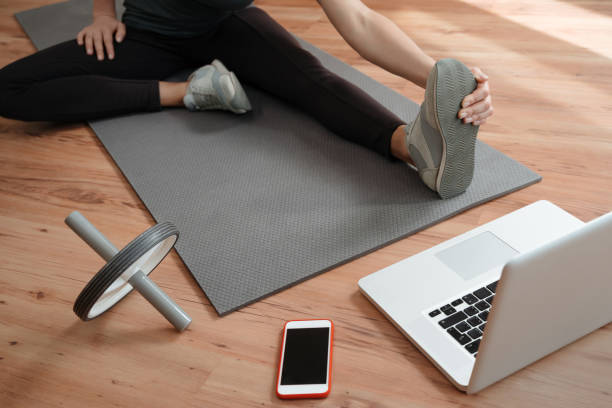 istock Young slim woman stretching legs during online training at home 1224676625