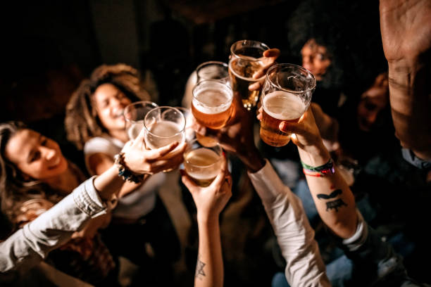 Friends toasting at pub Excited friends toasting with beer glasses at pub celebratory toast stock pictures, royalty-free photos & images