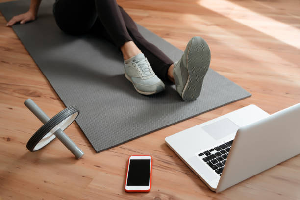 istock Sporty young woman sitting on exercise mat and watching online workout classes 1224676727