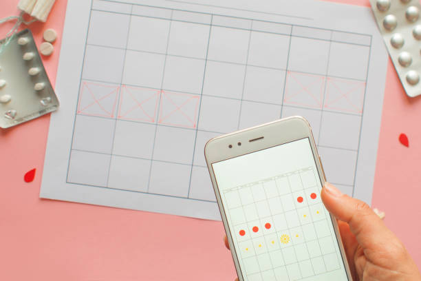 cycle menstruel. calendrier du mois avec des marques et une application mobile sur l’écran du smartphone. - menses photos et images de collection