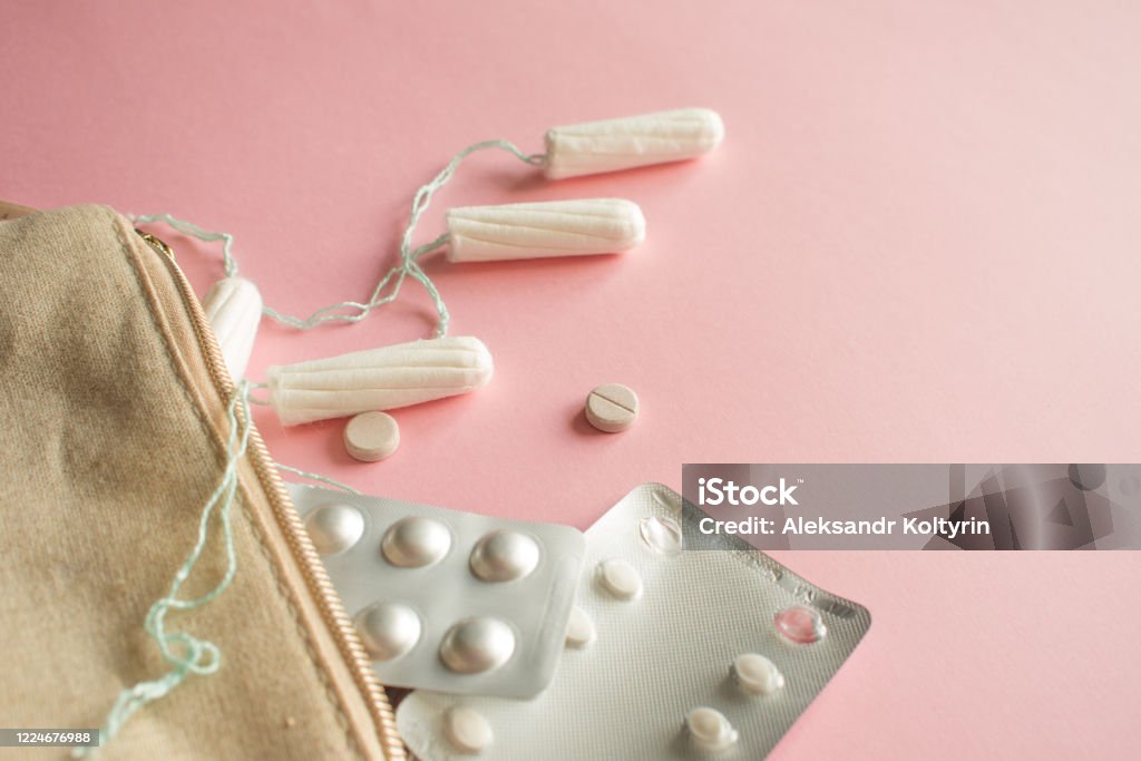 Cosmetic bag or handbag with tampons, contraceptives and pain pills. Set in case of menstruation. Cosmetic bag or handbag with tampons, contraceptives and pain pills. Set in case of menstruation. Pink background Backgrounds Stock Photo