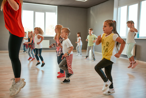 Estudiando danza moderna. Grupo de niños y niñas bailando mientras tienen una clase de coreografía en el estudio de baile. Profesora de danza y niños bailando photo