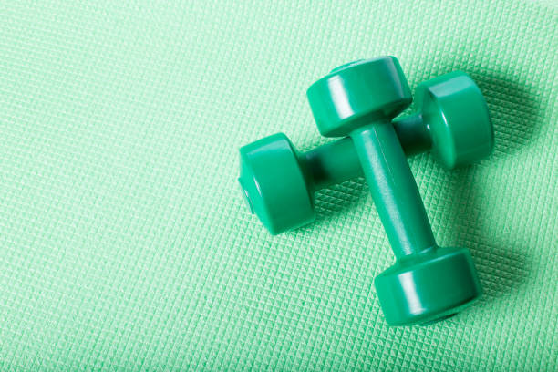 Green du,bbells on fitnes mat. Dumbbells with copy space