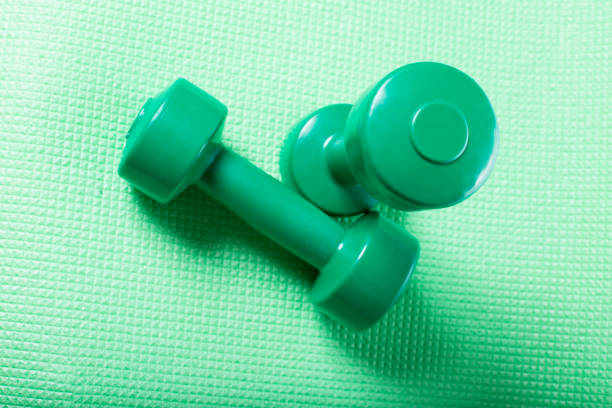 istock Fitnes dumbbells. Green dumbbells on karemat 1224678175