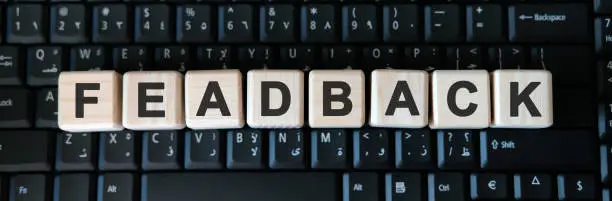 Photo of Feadback - business concept text on wooden cubes on background black keyboard