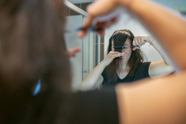 mujer cortando su propio cabello en días de cuarentena - bangs fotografías e imágenes de stock