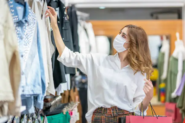 Photo of A young woman wears a protective mask while shopping at the Mall.