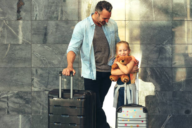 I am going on a trip with my dad Father and daughter standing together with their luggage at airport. Family of two going on a vacation. man with teddy bear stock pictures, royalty-free photos & images