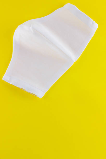 istock Protective gauze mask on a yellow background. White medical protective mask from cotton. Protective face mask made of gauze. Top view. Copy space 1224687286