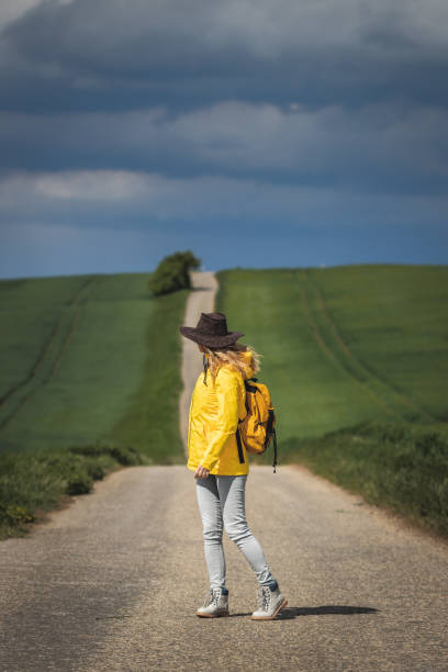 istock Woman hiking on road and looking at dramatic sky 1224688165