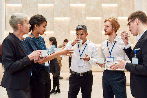 Group of businesspeople interacting during coffee break at business conference. Business, communication concept. Horizontal shot. Selective focus