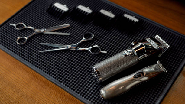 Scissors, electric hair trimmers and four different nozzles lying on a rubber mat in the barbershop. Professional barber tool kit Scissors, electric hair trimmers and four different nozzles lying on a rubber mat in the barbershop. Professional barber tool kit. Hairdressing equipment assembly kit stock pictures, royalty-free photos & images