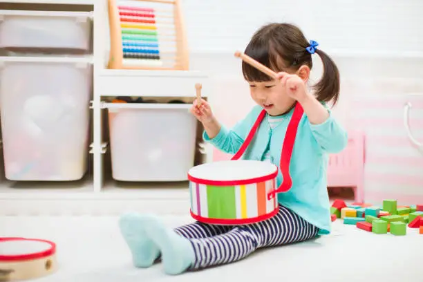 Photo of toddler girl play drum at home for homeschooling