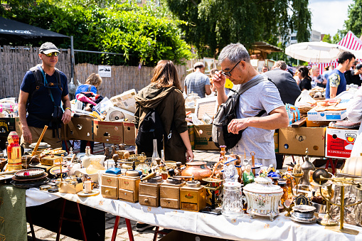 People searching the flea market for antiques and interesting buys at the Mauerpark. Mauerpark is a public park in the Prenzlauer Berg district. Flea market in Mauerpark is frequently used as sunday afternoon activity by hip Berliners and tourists. The flea market itself consists of mainly private salespersons who offer various items.