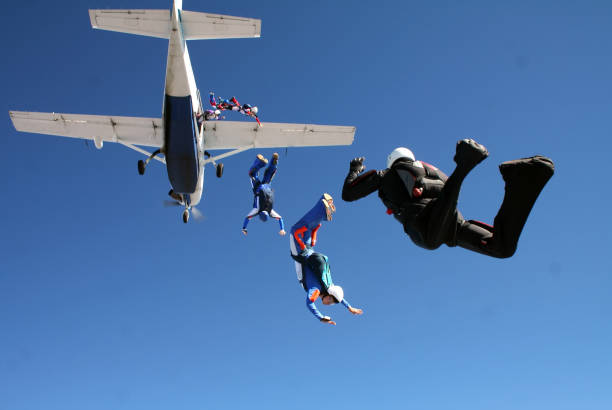 un gruppo di paracadutisti saltano insieme da un aereo contro il cielo blu. - skydiving parachuting extreme sports airplane foto e immagini stock