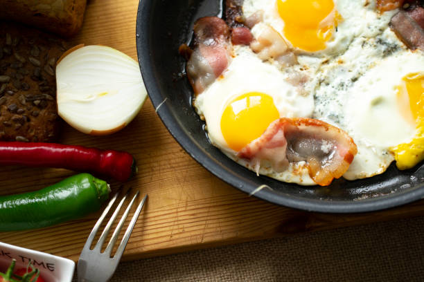 istock fried eggs with bacon in a pan. near cherry tomatoes chilli peppers rustic bread. 1224703161