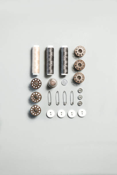 Sewing kit accessories and tools for needle work in gray. Tape measure, pins, scissors, buttons, prewound bobbins, thimble, thread cutter flat lay. Knolling same color concept.