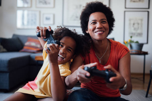 vista frontale di madre e figlia che giocano insieme ai videogiochi - video game family child playful foto e immagini stock