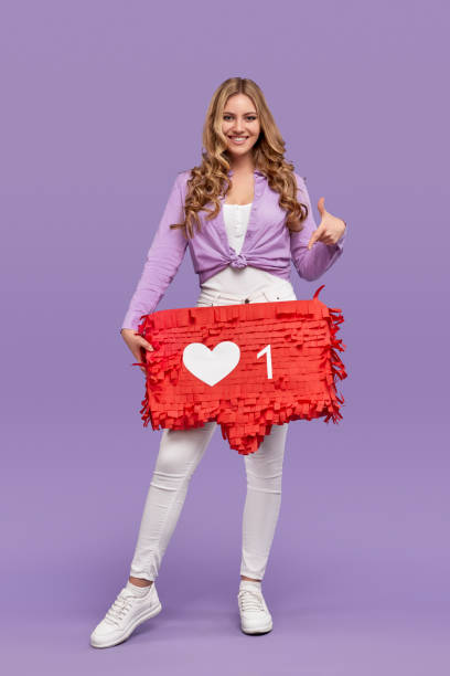 Happy modern woman pointing at speech bubble with heart icon