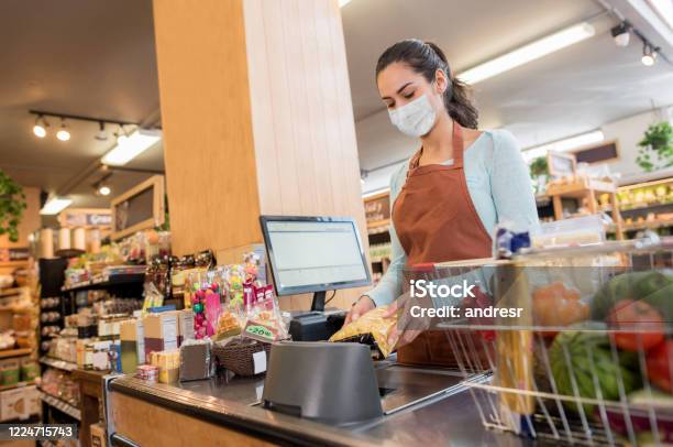 Cashier Working At The Supermarket Wearing A Facemask While Scanning Products Stock Photo - Download Image Now