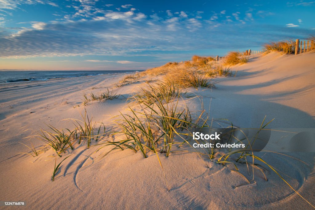 Azure blue sky and puffy clouds just after sunrise on the beach at Beach Haven Beautiful early morning beach scene with tufts of grass amid the sand dues on Long Beach Island New Jersey Stock Photo