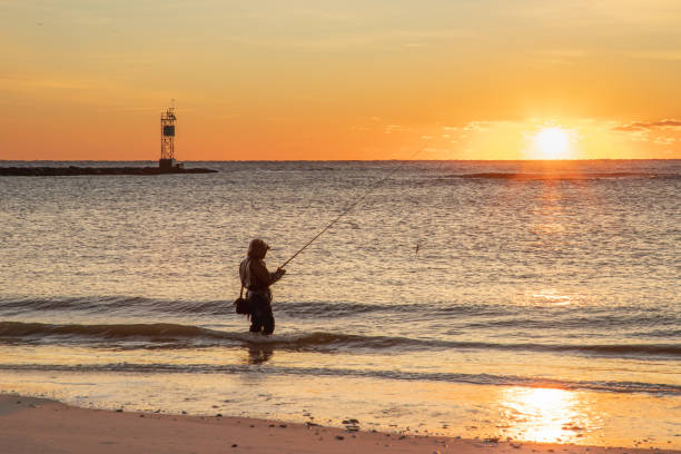 A lone surf-fisherman gets ready to cast at dawn at the north end of Long Beach Island stock photo