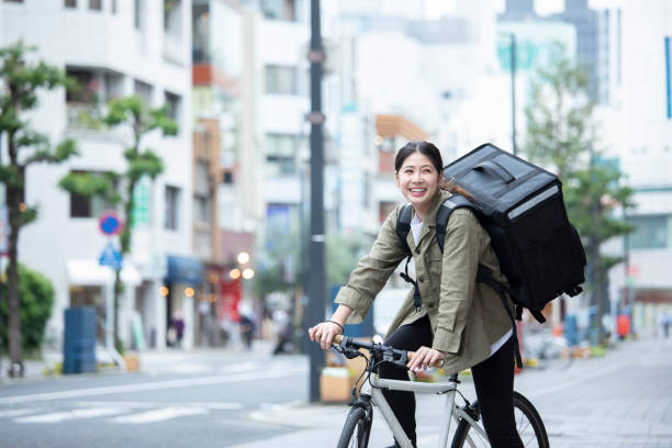 giovane donna che consegna bagagli in bicicletta - ethnicity cycle professional occupation business person foto e immagini stock