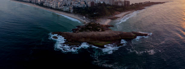istock Swirling ocean wave pattern at Arpoador rock in Rio de Janeiro, Brazil, with Ipanema beach and wider cityscape in the background against a colourful sky at sunrise 1224722533