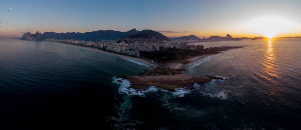 istock Swirling ocean wave pattern at Arpoador rock in Rio de Janeiro, Brazil, with Ipanema beach and wider cityscape in the background against a colourful sky at sunrise 1224729197