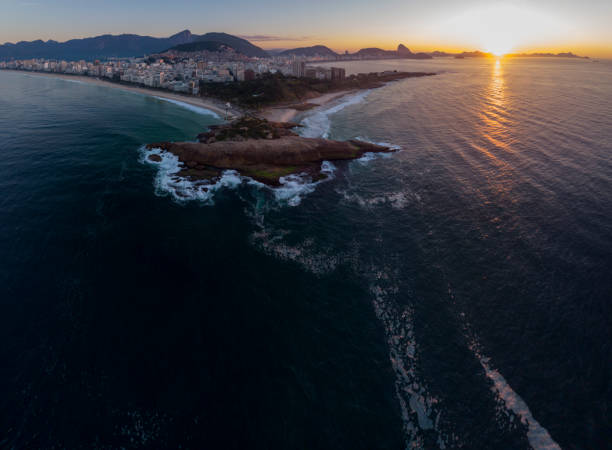 istock Swirling ocean wave pattern at Arpoador rock in Rio de Janeiro, Brazil, with Ipanema beach and wider cityscape in the background against a colourful sky at sunrise 1224733018