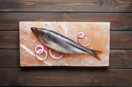 Fish herring with onions on a salt Himalayan block. Top view. Method of salting fish