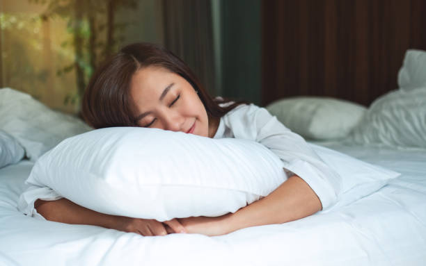 istock woman holding a pillow while sleeping in a white cozy bed at home 1224740725
