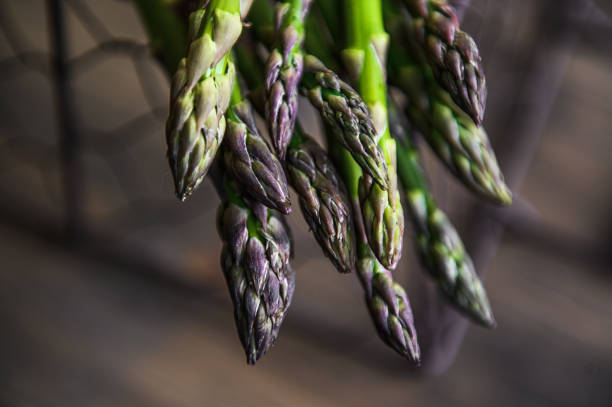 Bunch of fresh asparagus on the basket on a wooden table. Photo taken with selective focus.