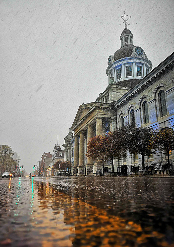 Late-Winter image of Kingston Ontario City Hall during Snowfall with rain and glossy wet street
